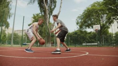 Sıcak bir yaz gününde sokak basketbolu oynayan insanlar. Güneşli bir yaz gününde açık hava sahasında basketbol oynayan iki genç. Saldırı ve savunma, atış yok..