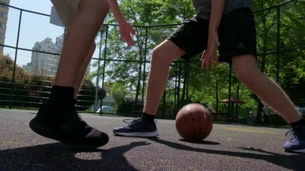 在温暖的夏天 人们在街上打篮球的视频 在阳光明媚的夏日 两名青少年在室外场地打一场篮球赛 攻击和防御 未射中 — 图库视频影像