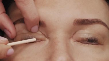 Profesyonel bir güzellik salonunda modern kirpik kaplama prosedüründe kadın yüzü. Usta, kirpik kıvırma prosedüründen önce özel yapıştırıcı sürerek kapatır. Güzellik salonu.