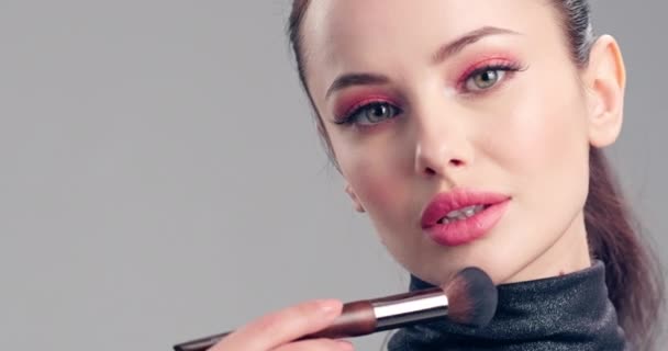 女は化粧する 若い女性は化粧ブラシを使って顔に赤面します 化粧品の概念 メイクを行う美しいブルネットのモデル 女の子は顔に化粧ブラシをかけている 4Kスローモーション映像 — ストック動画