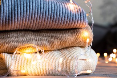 Üç örgü süveter, beyaz ve kahverengi ve bir çelenk.