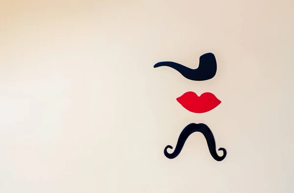 paper, red lips, black mustache on a beige background, top view