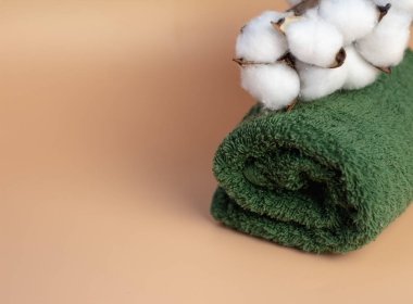 Yeşil, bej arka planda terry havlusu, pamuktan bir dal, yakın plan. Spa tedavileri