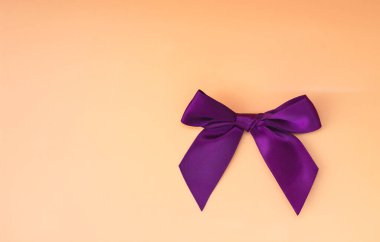 Üst görünümü (düz kaşık) bej bir arka planda izole edilmiş mor bir yay. Boşluğu kopyala.