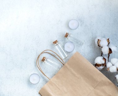 Beyaz arka planda küçük, şeffaf, cam bir şişe. Doğal, çevre dostu ürünler ve kozmetik ürünleri kavramı