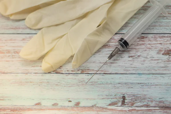 disposable syringe close-up with beige, latex gloves