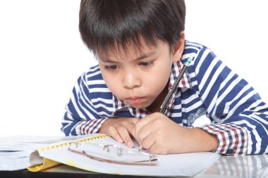 A young boy doing homework on a white background.