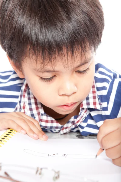 A young boy doing homework on a white background. — Stockfoto