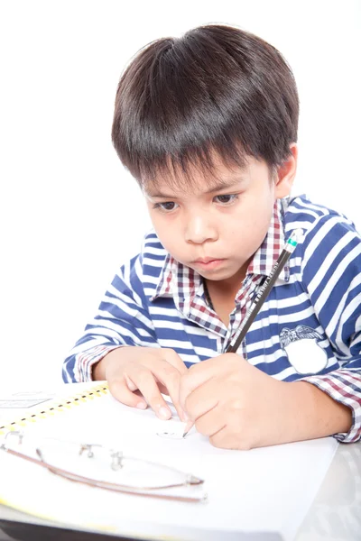 Ein kleiner Junge macht Hausaufgaben auf weißem Hintergrund. — Stockfoto