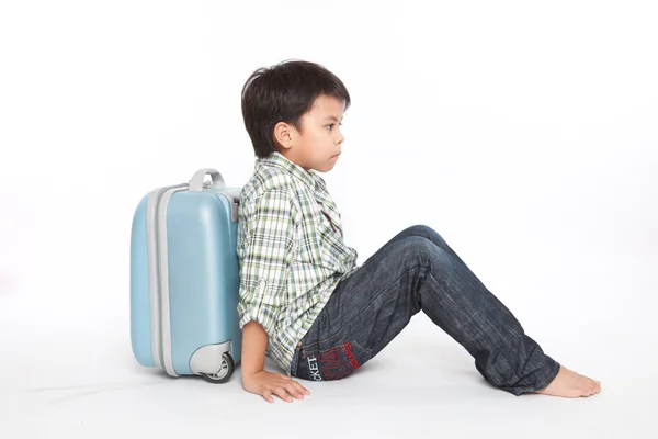 Мальчик с чемоданом стоит — стоковое фото