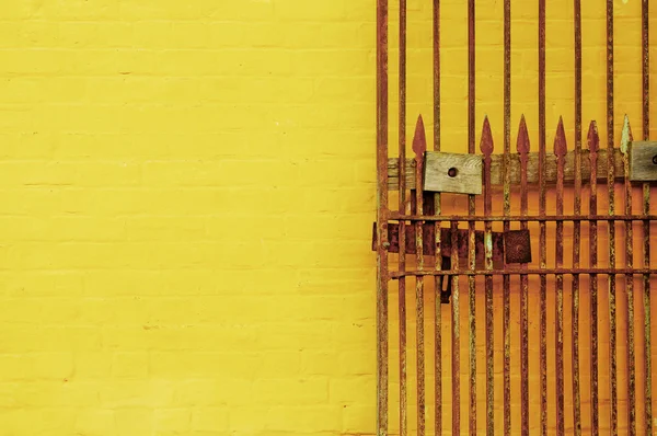 Rusty antique lock gate and bright yellow wall — Stock Photo, Image