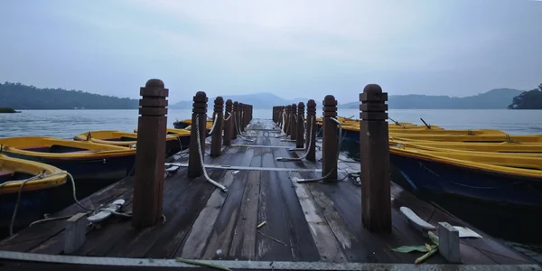 Barcos a remo e molhe de madeira pela manhã — Fotografia de Stock