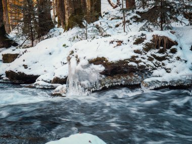 Nehrin donmuş arazide akışı. Donmuş nehirdeki donmuş kayalar.