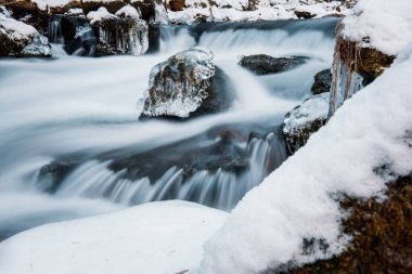 Nehrin donmuş arazide akışı. Donmuş nehirdeki donmuş kayalar.
