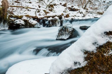 Nehrin donmuş arazide akışı. Donmuş nehirdeki donmuş kayalar.