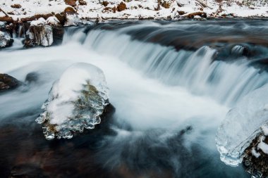 Nehrin donmuş arazide akışı. Donmuş nehirdeki donmuş kayalar.