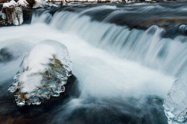 Nehrin donmuş arazide akışı. Donmuş nehirdeki donmuş kayalar.