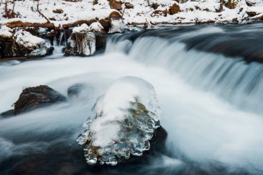 Nehrin donmuş arazide akışı. Donmuş nehirdeki donmuş kayalar.