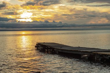 Sessiz bir yaz akşamında Onega gölünde günbatımı gökyüzünün arka planında ahşap balıkçı iskelesi.