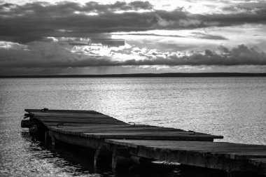 Sessiz bir yaz akşamında Onega gölünde günbatımı gökyüzünün arka planında ahşap balıkçı iskelesi.