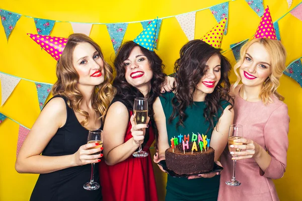 Portret van vrolijke vrienden roosteren en camera op verjaardagsfeestje te kijken. Aantrekkelijke vrienden vieren een verjaardag. Lachende meisjes met glazen champagne — Stockfoto