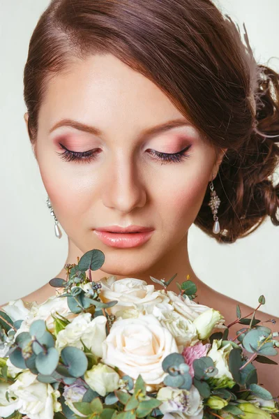 El retrato de la muchacha hermosa joven en la imagen de la novia con el ornamento en el peinado. La novia hermosa con el ramo mirando hacia abajo. Primer plano — Foto de Stock