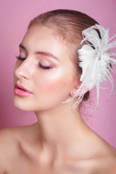 Retrato de novia hermosa.Retrato de una mujer hermosa en la imagen de la novia con plumas decorativas en el pelo. Foto tomada en el estudio sobre fondo rosa . — Foto de Stock