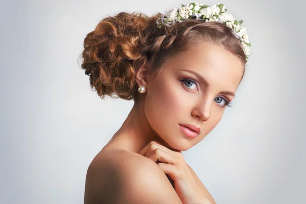 Hermosa joven con un adorno floral en su pelo.Hermosa mujer tocando su cara. Concepto de Cuidado de la Juventud y la Piel sobre fondo blanco —  Fotos de Stock