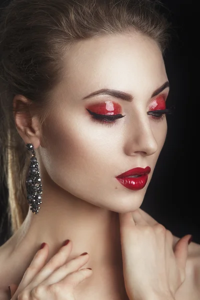 Элегантная молодая модель с красными губами и цветным вечерним макияжем на темном заднем плане. — стоковое фото