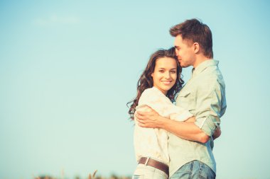 Young couple in love outdoor.Stunning sensual outdoor portrait of young stylish fashion couple posing in summer in field.Happy Smiling Couple in love.They are smiling and looking at each other