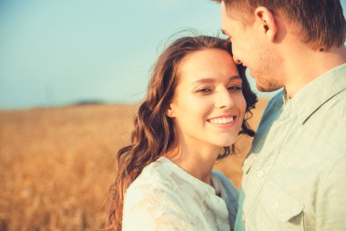 Young couple in love outdoor.Stunning sensual outdoor portrait of young stylish fashion couple posing in summer in field.Happy Smiling Couple in love.They are smiling and looking at each other
