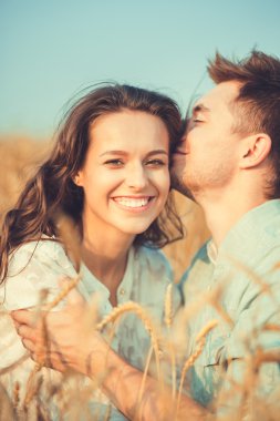 Young couple in love outdoor.Stunning sensual outdoor portrait of young stylish fashion couple posing in summer in field.Happy Smiling Couple in love.They are smiling and looking at each other