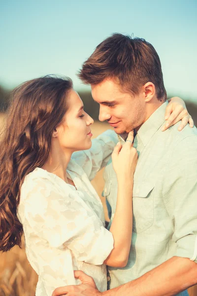 Young couple in love outdoor.Stunning sensual outdoor portrait of young stylish fashion couple posing in summer in field.Happy Smiling Couple in love.They are smiling and looking at each other