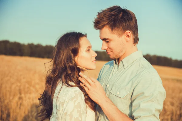 Young couple in love outdoor.Stunning sensual outdoor portrait of young stylish fashion couple posing in summer in field.Happy Smiling Couple in love.They are smiling and looking at each other — Stockfoto