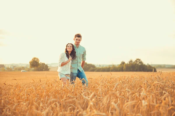 Young couple in love outdoor. Stunning sensual outdoor portrait of young stylish fashion couple posing in summer in field. Happy Smiling Couple in love. They are smiling and looking at each other — Stock Photo, Image