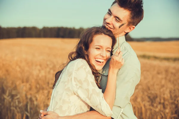 Jong koppel in liefde buiten. Schitterende sensuele outdoor portret van de jonge stijlvolle mode paar poseren in de zomer in veld. Gelukkige paar, glimlachen, in de liefde. Ze glimlachen en kijken naar elkaar — Stockfoto