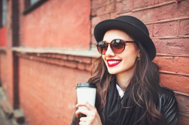 Trendy kadın güneş gözlüğü ile drinkoutdoor. Genç kadın güneş gözlüğü sokak ve elinde fincan kahve