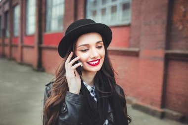 Young pretty girl in hat using smartphone.Woman using smartphone to make a call  in the street