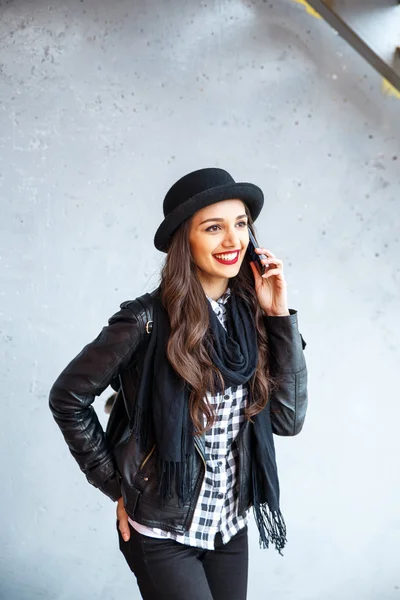 Jovencita bonita con sombrero usando smartphone para hacer una llamada en la calle . — Foto de Stock