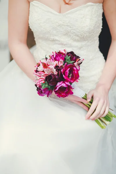 Novia sentada en el banco celebración de ramo de boda de varias flores . — Foto de Stock