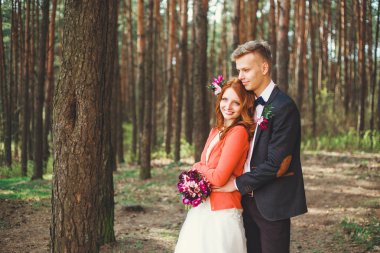 Parkta gelin ve damadın düğün fotoğrafı. Düğün çifti gelinlik buketi ile evlendi. Açık düğün töreninde şık mutlu gülümseyen yeni evliler. Aşık açık genç çift.