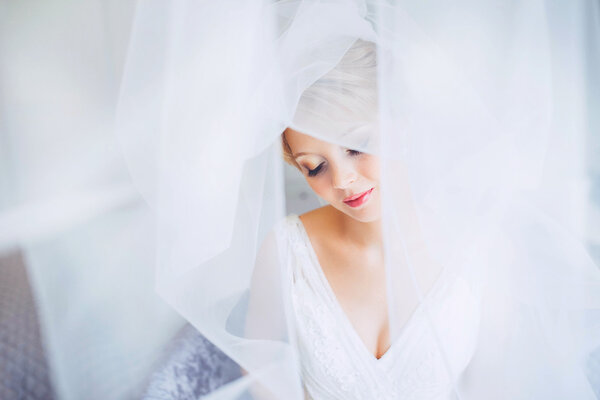 Молодая невеста со свадебным макияжем и прической в спальне. Крупный план портрета молодой великолепной невесты. Свадьба
.