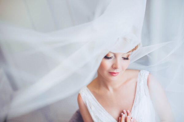 Молодая невеста со свадебным макияжем и прической в спальне. Крупный план портрета молодой великолепной невесты. Свадьба
.