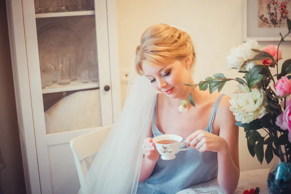 Schöne junge Braut mit Hochzeits-Make-up und Frisur im Schlafzimmer. Morgen der Braut. posiert am Hochzeitsmorgen auf dem Bett. schöne junge Frau in Vernachlässigung in der Früh Tee trinken. — Stockfoto