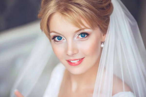 Hermosa novia joven con maquillaje de boda y peinado en bedroom.Beautiful retrato de novia con velo sobre su cara. Retrato de cerca de la joven novia hermosa. Boda . — Foto de Stock