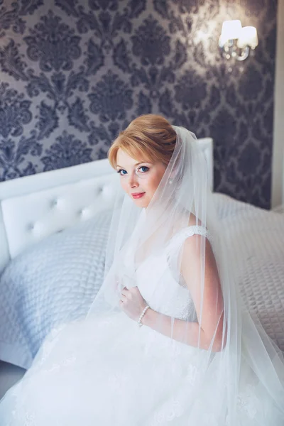 Schöne junge Braut mit Hochzeit Make-up und Frisur im Schlafzimmer. Schöne Braut Porträt mit Schleier über ihrem Gesicht. Nahaufnahme Porträt der jungen wunderschönen Braut. Hochzeit. — Stockfoto