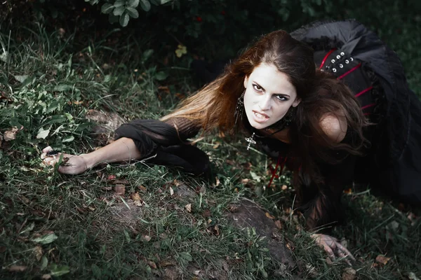 Strega di Halloween in una foresta buia. Bella giovane donna in costume da strega. Sfondo di orrore per il concetto di Halloween — Foto Stock