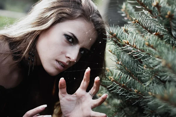 Halloween heks in een donker bos. Mooie jonge vrouw in heksen kostuum. Achtergrond van de horror voor Halloween Concept — Stockfoto
