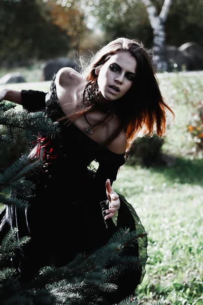 Bruja de Halloween en un bosque oscuro. Hermosa joven con disfraz de bruja. Fondo de horror para el concepto de Halloween — Foto de Stock