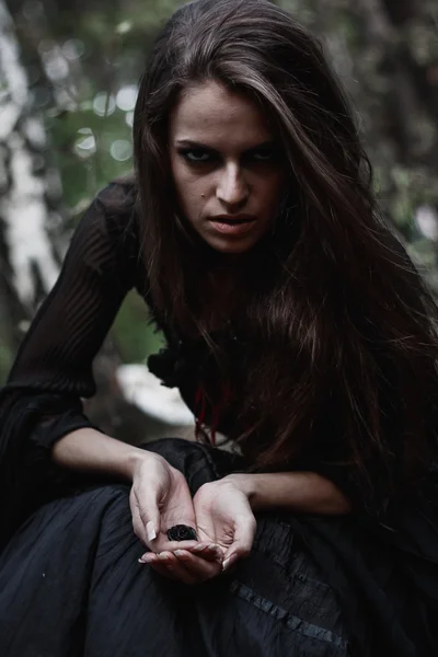 Strega di Halloween in una foresta buia. Bella giovane donna in costume da strega. Sfondo di orrore per il concetto di Halloween — Foto Stock